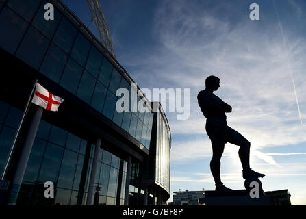 Eine englische Flagge, die hinter der Statue von Sir Bobby Moore vor Wembley vor dem International Friendly im Wembley Stadium, London, fliegt. DRÜCKEN Sie VERBANDSFOTO. Bilddatum: Mittwoch, 3. September 2014. Siehe PA Geschichte FUSSBALL England. Bildnachweis sollte lauten: Adam Davy/PA Wire. Stockfoto