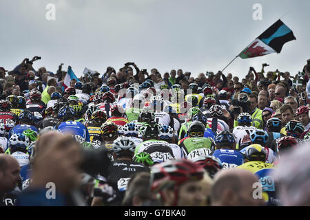Die Massen mischen sich mit dem Hauptfeld, während sie während der fünften Etappe der Tour of Britain 2014 unter dem Hay Tor während eines Bergaufstiegs auf Dartmoor, Devon, zusehen. Stockfoto