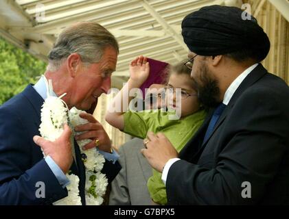 Der britische Prinz Charles (links) wird von der 4-jährigen Tauleen mit einem haar überreicht, wie sie von ihrem Vater Dr. Balwinder Singh (rechts) gehalten wird. Als er zur Feier des 400. Jahrestages der ersten Lesung der Guru Granth Sahib Sikh Schrift in der Royal Albert Hall in London kommt. Die Veranstaltung wurde vom Netzwerk der Sikh-Organisationen organisiert, um dem 400. Jahr des heiligen Buches von Sikh, dem Guru Granth Sahib, zu gedenken, einer Sammlung der Verse des Sikh Gurus. Stockfoto