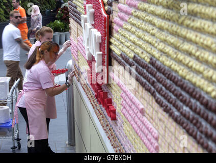 Ein Team von Food-Künstlern verschönern ein essbares Poster aus über 13,000 Mr Kipling Cakes - mit der Aufschrift "Life is Better with Cake", das im Westfield London Shopping Centre in Shepherds Bush installiert wurde. Stockfoto