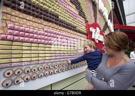 Gemma Goodfellow und ihr Sohn Sam, 1, sehen sich ein essbares Poster an, das von über 13,000 Mr Kipling Cakes angefertigt wurde - mit der Aufschrift „Life is Better with Cake“, das im Westfield London Shopping Centre in Shepherds Bush installiert wurde. Stockfoto