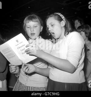 Zwei Londoner Schülerinnen, die am ersten Tag des Weihnachtsliedes-Festivals der Londoner Schulen in der Royal Festival Hall, South Bank, London, singen, sind zweifellos bereits voll von Gedanken an Cracker und Pflaumenpudding. Es waren zwei von 3,000 Kindern, die daran teilnahmen. Bis zum Ende des Festivals in der nächsten Woche werden etwa 18,000 Jugendliche aus London daran teilgenommen haben. Stockfoto