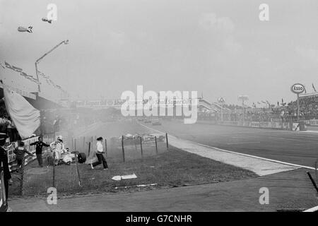 Der italienische Rennfahrer Andrea de Cesaris läuft von seinem Marlboro McLaren ab, nachdem das Auto nach einem Zwischenfall in der vierten Runde des Grand Prix von Großbritannien in Silverstone beim Fechten abgestürzt ist. Der Williams des Australiers Alan Jones, des amtierenden Weltmeisters, landete ebenfalls von der Strecke, nachdem sich der Ferrari von Gilles Villeneuve aus der Woodcote-Schikane drehte. Der in Belfast geborene John Watson von McLaren gewann das Rennen. Stockfoto