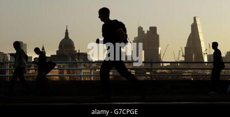 Pendler am frühen Morgen überqueren die Waterloo Bridge in London, wenn die Sonne aufgeht. Stockfoto