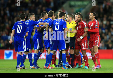 Die Spieler von Wales und Bosnien und Herzegowina kämpfen, während Schiedsrichter Vladislav Bezborodow während des UEFA-EM-2016-Spiels im Cardiff City Stadium, Cardiff, kämpft, um die Kontrolle zu behalten. Stockfoto