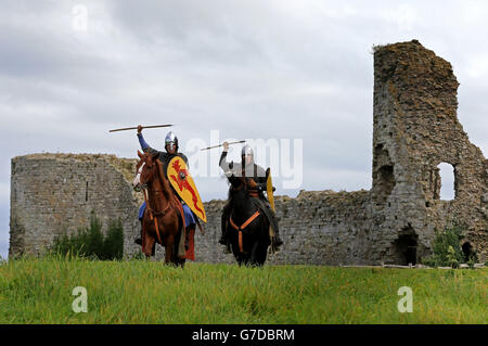 Zwei normannische Kavallerie-Reenaktoren tragen genietete maille Hauberks, Und mit Schwertern, Schilden und Lanzen von Pevensey Castle in East Sussex, um über zwei Tage von der Gegend, wo die Normannen landeten zu Battle Abbey und dem Ort der Schlacht von Hastings reiten, vor der Nachstellung der Schlacht von Hastings 1066 später in diesem Monat. Stockfoto