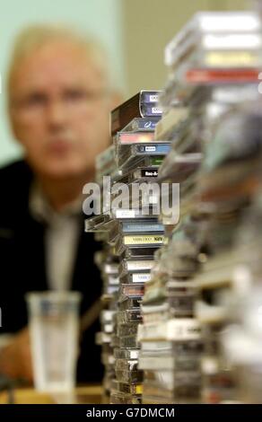 Ein Stapel von CDs sitzt vor dem Musikimpressario Pete Waterman, als er an einer Pressekonferenz in den Büros der britischen Phonographischen Industrie im Zentrum von London teilnimmt. Das BPI und sein internationales Pendant das IFPI verkündeten eine große Eskalation ihrer Kampagne gegen illegale Feueraufteilung und zielten auf große Uploader ab, die illegal Copright-Musik im Internet zur Verfügung stellen. Stockfoto