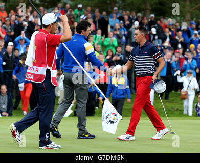 Der europäische Rory McIlroy (Mitte) trifft den US-amerikanischen Rickie Fowler, nachdem er sein Einzelspiel am dritten Tag des 40. Ryder Cup auf dem Gleneagles Golf Course, Perthshire, gewonnen hat. Stockfoto