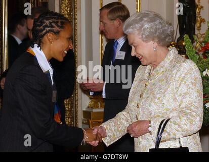 Die britische Königin Elizabeth II. Wirft einen Blick auf die Medaillen von Kelly Holmes, als sie sie bei einem Empfang für olympische und paralympische Athleten im Buckingham Palace in London empfängt. Stockfoto