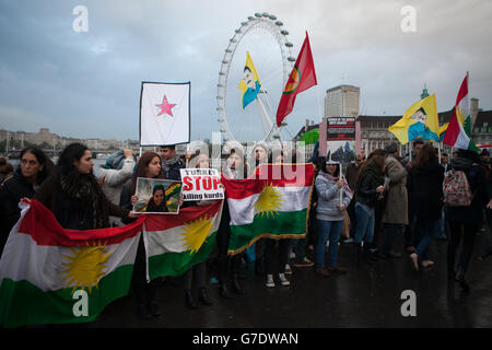 Menschen demonstrieren auf der Westminster Bridge im Zentrum von London mit kurdischen Fahnen und Transparenten gegen die Bedrohung der Kurden und anderer Minderheiten in Syrien und im Irak durch den IS. Stockfoto