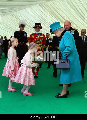 Königin Elizabeth II. Erhält von der fünfjährigen Ashlynne Kingshot (Mitte) und ihrem Cousin Leah, 6, (links) bei einem Besuch des Herzogs von Edinburgh im Tower of London eine Posty, um die Installation Blood Swept Lands and Seas of Red zu sehen, Das ist der hundertste Jahrestag des Ausbruchs des Ersten Weltkriegs. Stockfoto