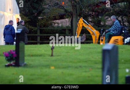 Polizeibeamte von Wiltshire bringen einen Bagger auf dem Mayshill-Friedhof in Nibley, Nr Yate in South Gloucestershire, ein, während ein Marquee über dem Grab von Stephen Smith aufgesetzt wird, soll sein Leichnam für die polizeiliche Untersuchung ausgegraben werden. Stockfoto