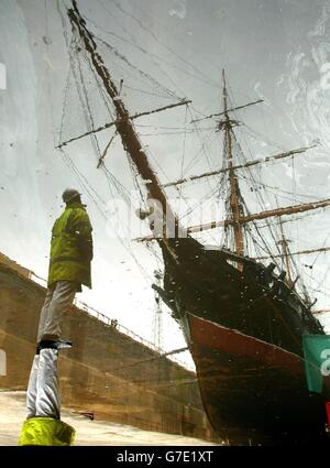 Ein Ingenieur bewundert HMS Warrior, Großbritanniens erstes eisernes Kriegsschiff in einem Trockendock in Portsmouth. Das 144 Jahre alte Schiff wird drei Wochen lang auf der Werft der Marine restauriert werden. Stockfoto