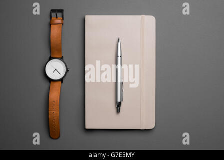 Draufsicht der Uhr und Notizbuch mit Stift auf grauem Hintergrund Stockfoto