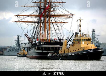 HMS Warrior, Großbritanniens erstes eisernes Kriegsschiff, wird von Schleppern an den Fregatten der Royal Navy vorbeigeschleckt, während sie in Richtung Trockendock in Portsmouth fährt. Das 144 Jahre alte Schiff wird drei Wochen lang auf der Werft der Marine restauriert werden. Stockfoto