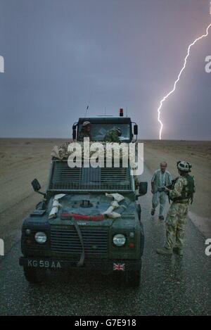 Ein Soldat der Dragoon Guards der Königin warnt einen irakischen Fahrer bei einem Gewitter, um seine Scheinwerfer abzuschalten, damit er nicht von feindlichem Feuer getroffen wird. Die Fahrzeuge befanden sich in einem Konvoi der britischen Armee, der über Nacht von Basra zur Black Watch Battle-Gruppe im Camp Dogwood, 20 Meilen südwestlich von Bagdad, reiste. Stockfoto