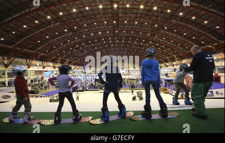 Kinder, die einen Snowboardkurs auf der trockenen Skipiste bei der Ski- und Snowboardshow im Earls Court in London machen. Stockfoto