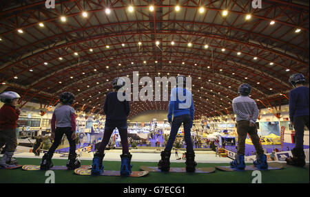 Kinder, die einen Snowboardkurs auf der trockenen Skipiste bei der Ski- und Snowboardshow im Earls Court in London machen. Stockfoto