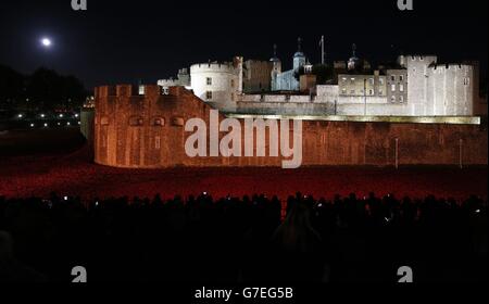 Die Öffentlichkeit hält an, um sich die Keramikmohn anzusehen, die Teil der Kunstinstallation „Blood Swept Lands and Seas of Red“ des Künstlers Paul Cummins im Tower of London sind und den hundertsten Jahrestag des Ersten Weltkriegs feiern. Stockfoto