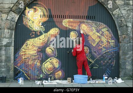 Ein Graffiti-Künstler bringt den letzten Schliff für ein Stück von Schottlands größtem Street-Art-Projekt im Herzen der Altstadt von Edinburgh, wo eine Reihe von ständig wechselnden Leinwänden fast einen halben Kilometer lang sein wird. Stockfoto