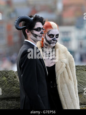 Ein Paar posiert für Fotografen auf dem Gelände der St. Mary's Church während des Whitby Goth Weekend in North Yorkshire. Stockfoto