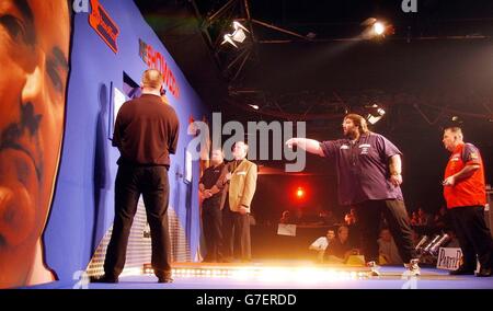 Andy Fordham am ocky (links), während Phil 'The Power' Taylor während des Kopf-an-Kopf-Showdowns im Circus Tavern, Purfleet, anschaut. Fordham hat den Nachteil, mit einem gebrochenen Handgelenk zu spielen. Stockfoto