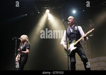 Die Gitarristen Rick Parfitt (L) und Francis Rossi von der Rockgruppe Status Quo auf der Bühne, während ihres Konzerts in der Wembley Arena in London. Stockfoto