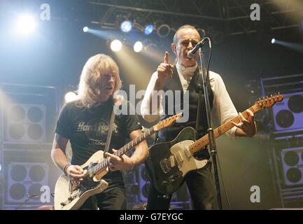 Die Gitarristen Rick Parfitt (L) und Francis Rossi von der Rockgruppe Status Quo auf der Bühne, während ihres Konzerts in der Wembley Arena in London. Stockfoto