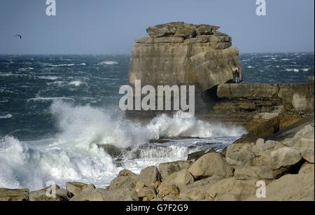 Ein Mitglied der Öffentlichkeit trotzt den Bedingungen, um ein Foto von der stürmischen See vor Portland Bill in Dorset zu machen, als die Überreste des Hurrikans Gonzalo in Großbritannien blies, was für Rush-Hour-Reise Elend für Straßen-, Schienen- und Flugreisende verursacht. Stockfoto