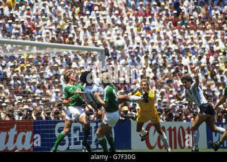 Argentiniens Diego Maradona (c) in der Westdeutschen Box als Torwart Harald Schumacher versucht, den Ball zu räumen. Ebenfalls für die Bundesrepublik abgebildet sind die Verteidiger Karlheinz Forster und Andreas Brehme. Stockfoto