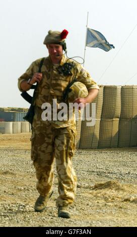 Ein Soldat des 1. Bataillons Black Watch geht an einer Saltyre-Fahne vorbei, die am Halbmast in Camp Dogwood, Irak, fliegt, nachdem am Donnerstag drei Black Watch-Soldaten durch die Selbstmordfahrzeugbombe getötet wurden. Stockfoto