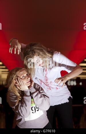 Menschen, die als Zombies verkleidet sind, jagen die Teilnehmer während eines Zombie-Laufs im Ealing Broadway Shopping Centre im Westen Londons, um Geld für die lokale Wohltätigkeitsorganisation The Log Cabin zu sammeln. Stockfoto