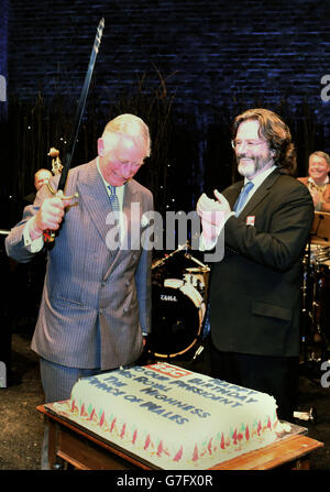 Der Prinz von Wales, Präsident des RSC, schneidet einen Geburtstagskuchen mit einem Schwert, nachdem er ihm zu seinem 66. Geburtstag bei einem Besuch des Swan Theatre in der Royal Shakespeare Company in Stratford upon Avon, Warwickshire, zur jährlichen Generalversammlung des RSC überreicht wurde. Stockfoto