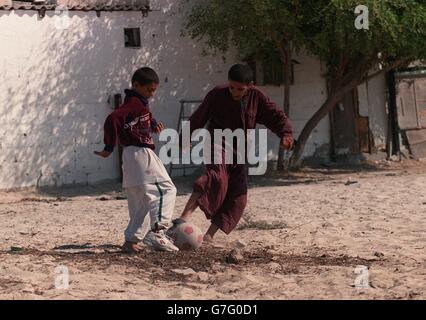 Kinder spielen Sport in Dubai, Vereinigte Arabische Emirate. Kinder spielen Fußball im Sand in Dubai Stockfoto