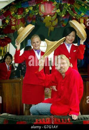 Sir Richard Branson, Vorsitzender von Virgin Atlantic, mit zwei Flughostessen auf einem Trödelboot in der Bucht von Hongkong. Sir Richard ist in Hongkong, um für die neueste Streckenführung der Fluggesellschaft zu werben, einen täglichen Nonstop-Service zwischen Hongkong und Sydney, der Verbindungen nach London bietet. Die neue tägliche Fluglinie wird mit Airbus 340-600-Flugzeugen bedient. Stockfoto