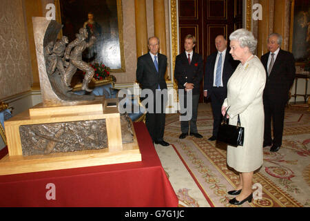 Queen Elizabeth II, am Buckingham Palace, mit einer Maquette des Battle of Britain Monument, das die Flieger ehren wird, die unter RAF Fighter Command in der Schlacht zwischen Juli und Oktober 1940 gekämpft haben. Die Maquette wurde von links nach rechts vom Vorsitzenden des Battle of Britain Monument Committee, Lord Tebbit, dem Bildhauer Paul Day, dem Gründer der Battle of Britain Historical Society, Bill Bond und Maurice Djanogly, dem stellvertretenden Vorsitzenden des Komitees, präsentiert Stockfoto