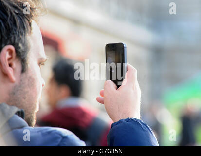 Ein allgemeines Stockfoto eines Mannes, der ein Foto mit seinem Mobiltelefon im Zentrum von London gemacht hat. Stockfoto