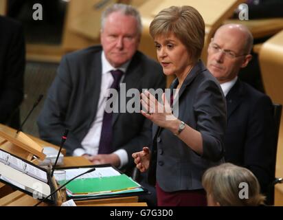 Schottlands erste Ministerin Nicola Sturgeon mit Finanzsekretär John Swinney (rechts) und Gesundheitssekretär Alex Neil (links) während ihres Debüts First Minster's Questions (FMQ's) in der Debattierkammer des schottischen Parlaments in Edinburgh, nachdem sie das Amt des ehemaligen Führers Alex Salmond übernommen hatte. Stockfoto