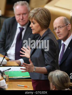 Schottlands erste Ministerin Nicola Sturgeon mit Finanzsekretär John Swinney (rechts) und Gesundheitssekretär Alex Neil (links) während ihres Debüts First Minster's Questions (FMQ's) in der Debattierkammer des schottischen Parlaments in Edinburgh, nachdem sie das Amt des ehemaligen Führers Alex Salmond übernommen hatte. Stockfoto