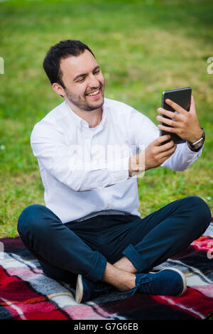 Moderne junge hispanic Mann unter ein Selbstporträt im Park, mit seinem Tablet. Stockfoto