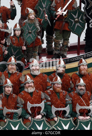 Mitglieder der Jarl Squad in Wikingerkostümen mit einer Wikingergaleere in Lerwick auf den Shetland Inseln während des Up Helly AA Viking Festivals. Stockfoto