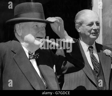 Sir Winston Churchill genießt eine Zigarre nach dem Mittagessen, als er mit Premierminister Harold Macmillan die 10 Downing Street verlässt. Stockfoto