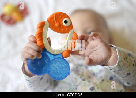 Ein 5 Monate altes Baby hält einen Beißring im Stil eines Fisches. Stockfoto