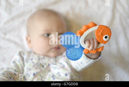 Ein 5 Monate altes Baby hält einen Beißring im Stil eines Fisches. Stockfoto