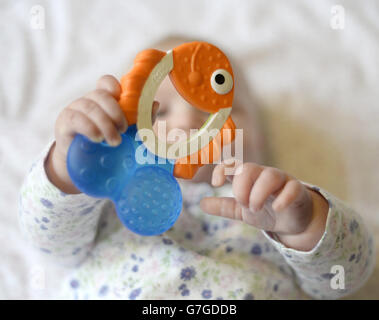 Ein 5 Monate altes Baby hält einen Beißring im Stil eines Fisches. Stockfoto