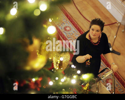 Die Kuratorin des Royal Collection Trust Sally Goodsir bringt den letzten Schliff an einen sechs Meter langen Nordman-Tannenbaum aus dem Windsor Great Park, der Teil der Weihnachtsausstellung in St. George's Hall im Windsor Castle in Berkshire ist. Stockfoto