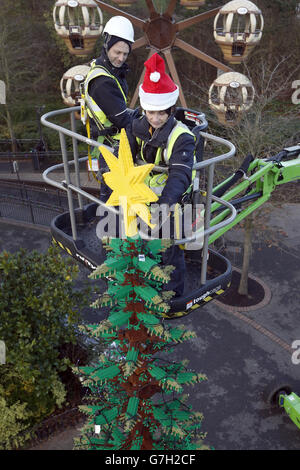 Modellbauer Katrina James (rechts) platziert einen LEGO Stern auf einem acht Meter hohen Weihnachtsbaum aus 300,000 Steinen im Legoland Windsor Resort in Berkshire. Stockfoto