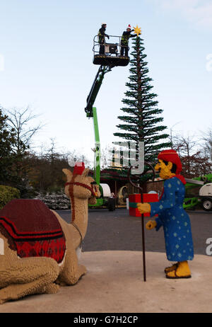 Modellbauer Katrina James (rechts) platziert einen LEGO Stern auf einem acht Meter hohen Weihnachtsbaum aus 300,000 Steinen im Legoland Windsor Resort in Berkshire. Stockfoto