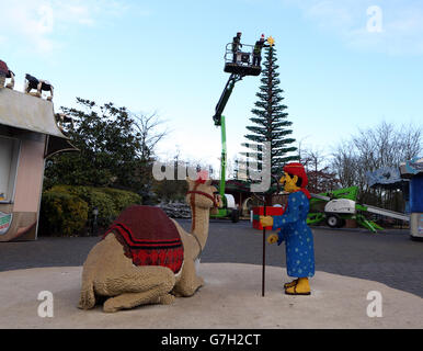 Modellbauer Katrina James (rechts) platziert einen LEGO Stern auf einem acht Meter hohen Weihnachtsbaum aus 300,000 Steinen im Legoland Windsor Resort in Berkshire. Stockfoto