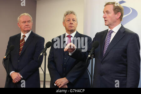 Taoiseach Enda Kenny spricht mit den Medien, während der stellvertretende Premierminister von Nordirland, Martin McGuinness (links), und der erste Minister von Nordirland, Peter Robinson, auf das Treffen des Nord-Süd-Ministerrats in Armagh blicken. Stockfoto